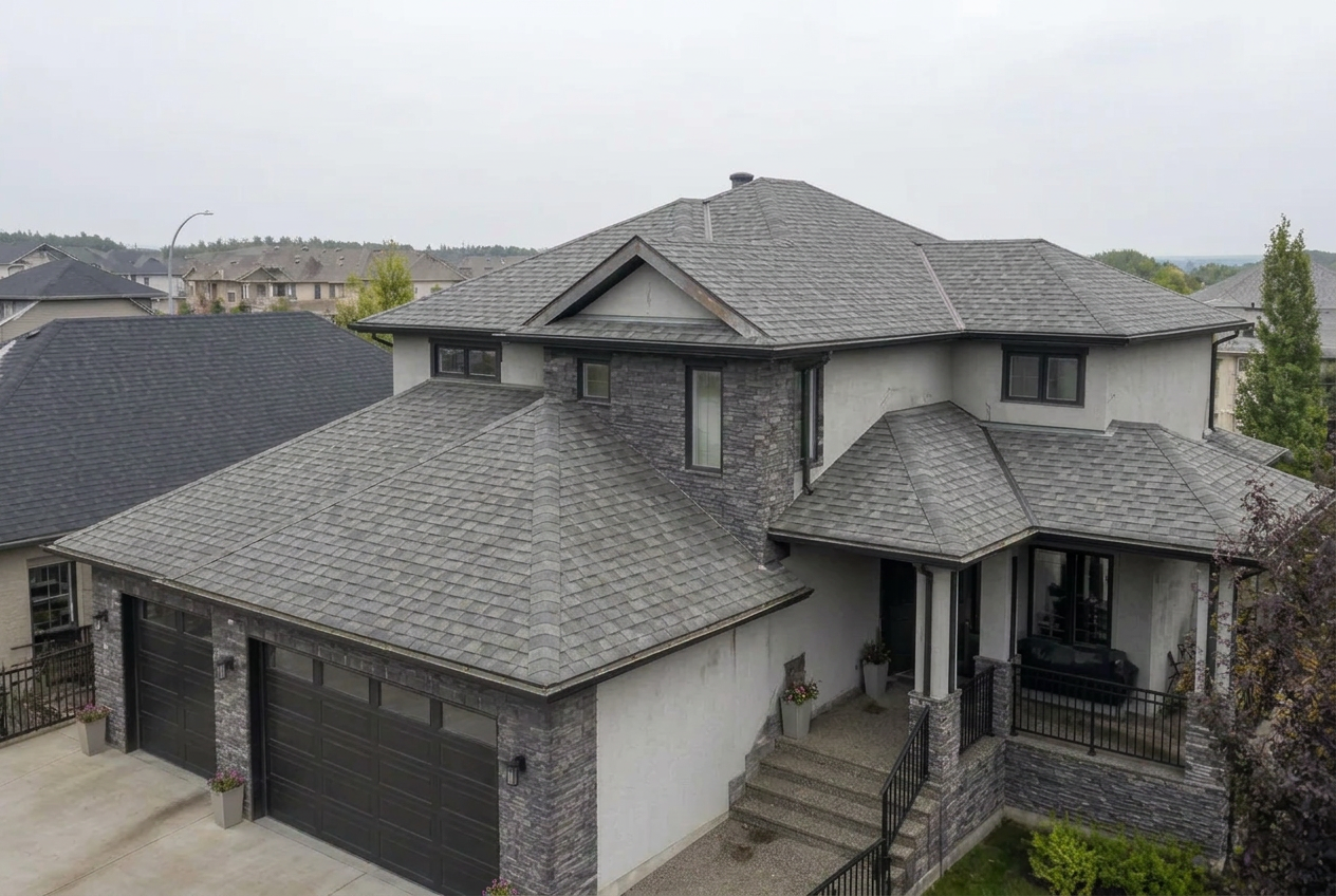 Aerial view of an aging Calgary roof with faded grey shingles and normal wear before replacement