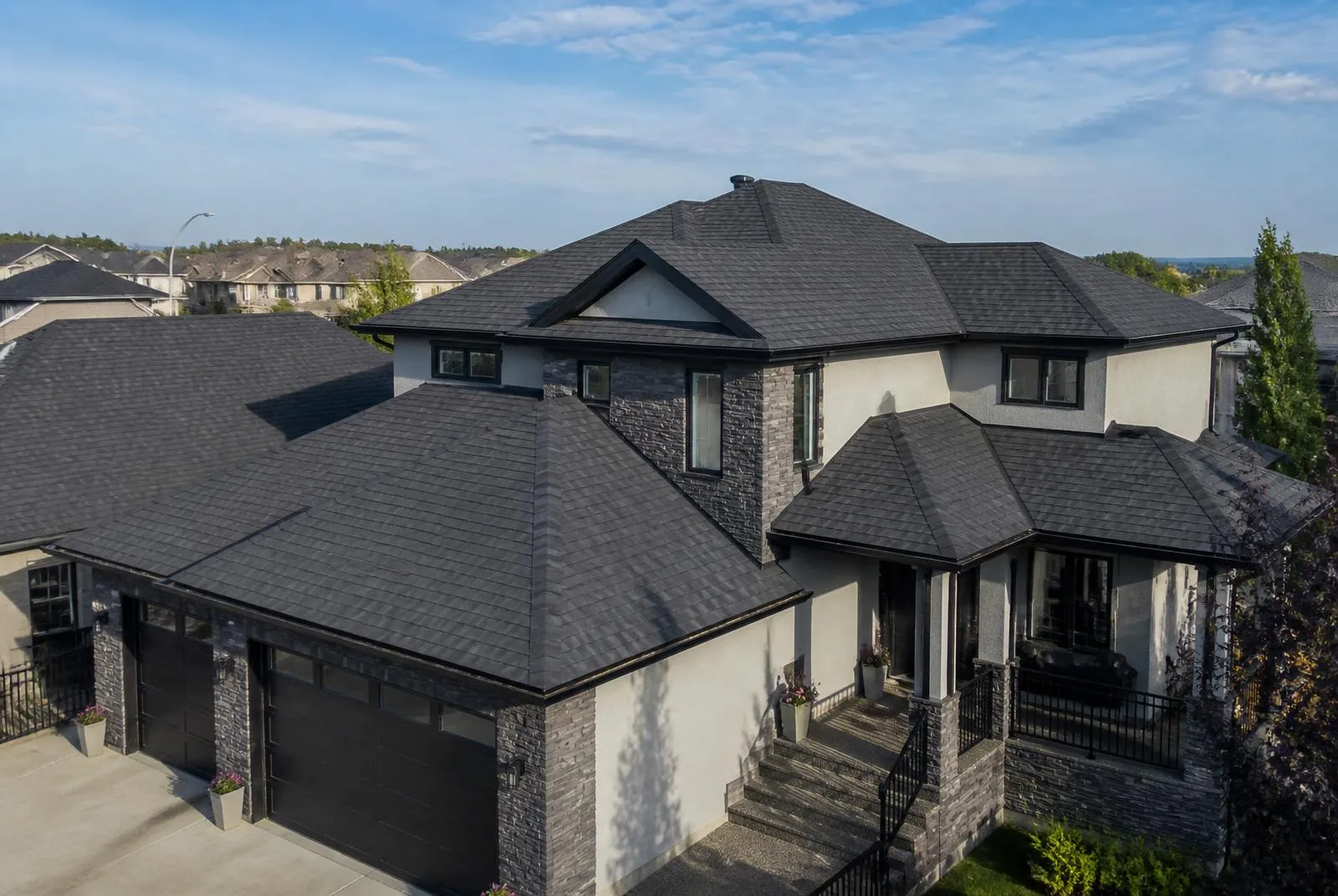 The same Calgary home after a full dark charcoal architectural shingle roof replacement